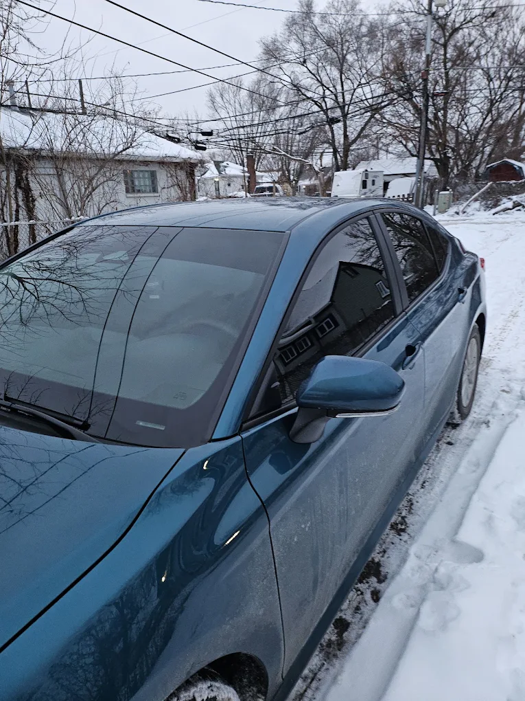 Blue sedan parked snowy street